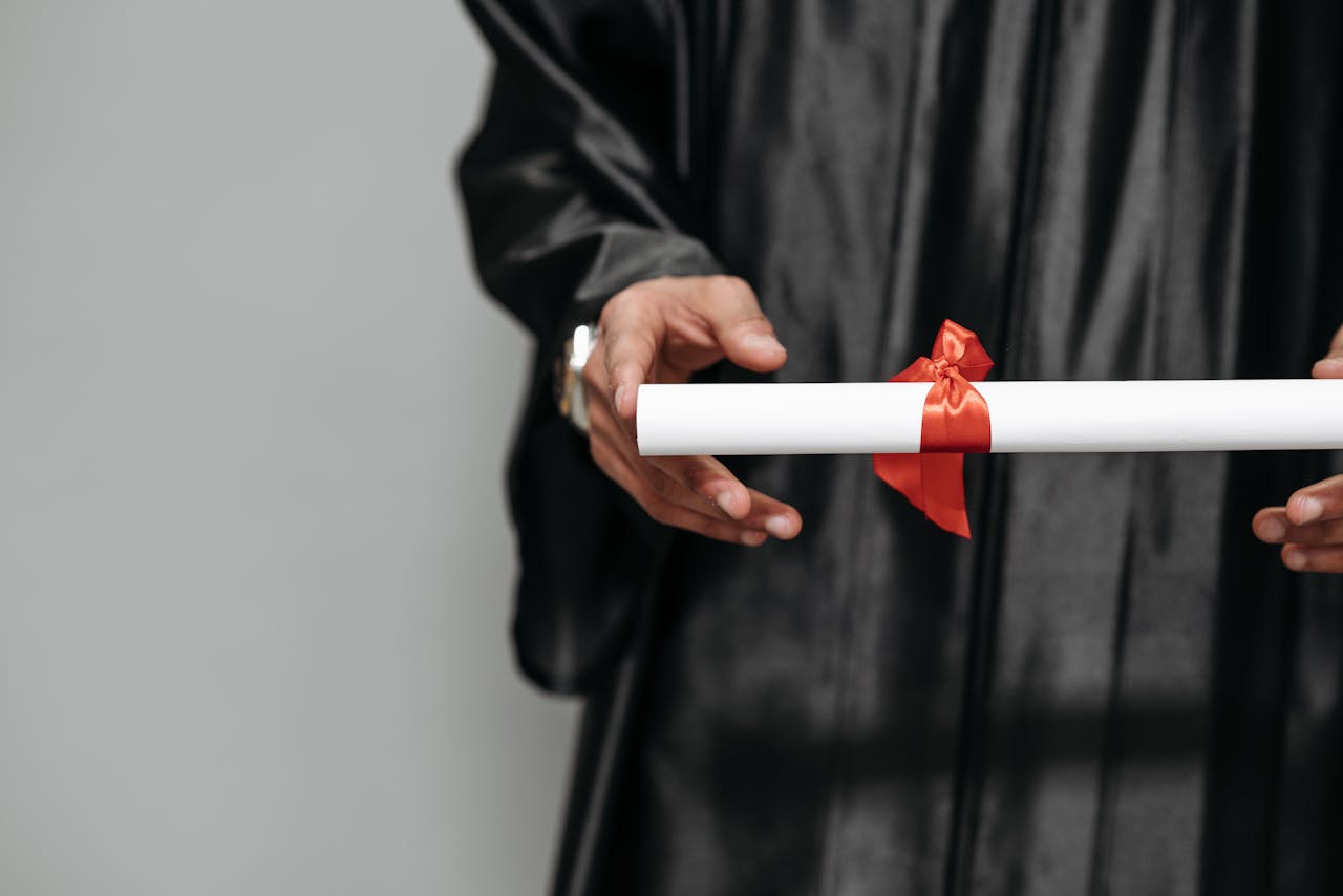services-02 Close-up of a graduate holding a diploma tied with a red ribbon, symbolizing achievement.