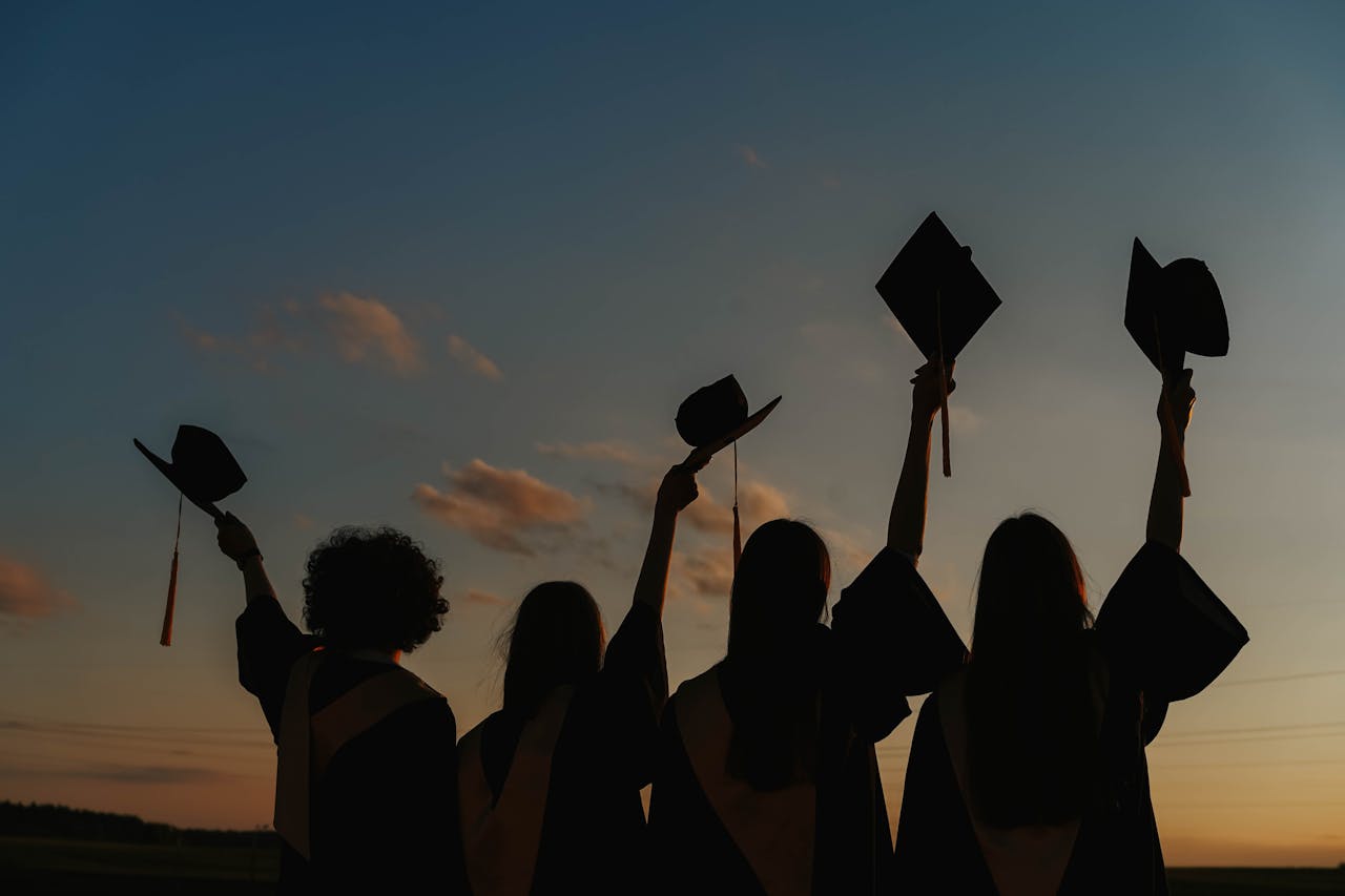 services-01 Silhouette of graduates raising caps in joy at sunset.